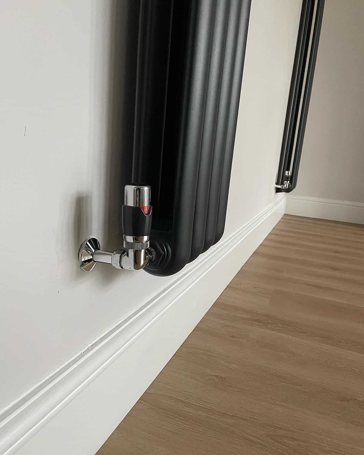 Close-up of modern radiator with control valve in room setting.